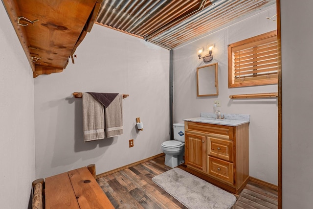 bathroom featuring vanity, wood finished floors, toilet, and baseboards