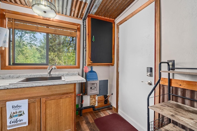 interior space featuring dark wood-style flooring, a sink, baseboards, light countertops, and brown cabinets