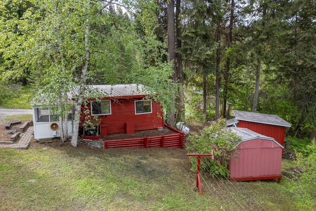 rear view of house with an outbuilding, a forest view, and a storage shed