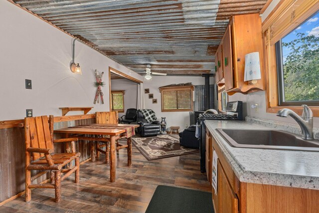 kitchen with dark wood-style flooring, a sink, light countertops, brown cabinetry, and stainless steel range with gas stovetop