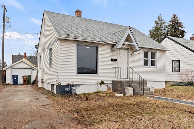 view of front of home with a chimney, roof with shingles, an outdoor structure, and a garage