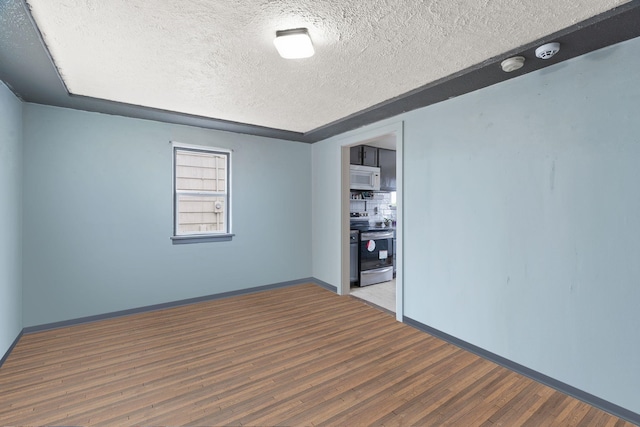 unfurnished room featuring a textured ceiling, baseboards, and wood finished floors