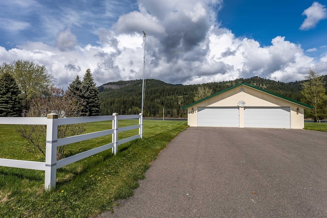 exterior space with a detached garage, fence, an outdoor structure, a mountain view, and a wooded view