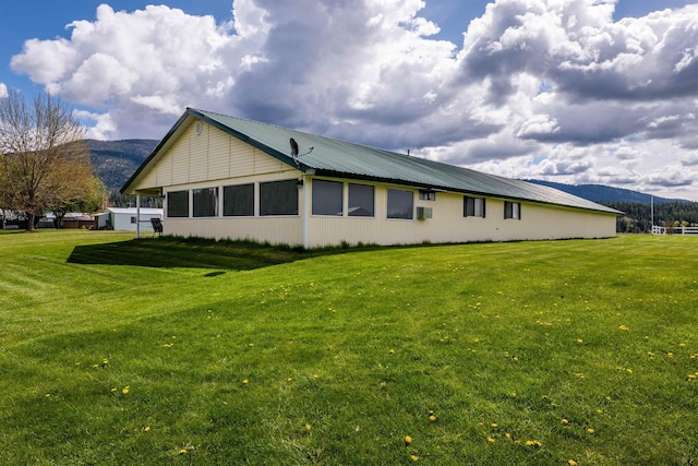 view of side of property featuring metal roof, a lawn, and a mountain view