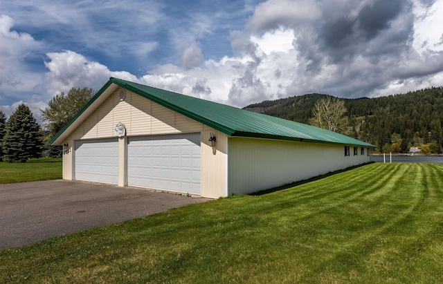 view of property exterior with metal roof, a yard, and a detached garage