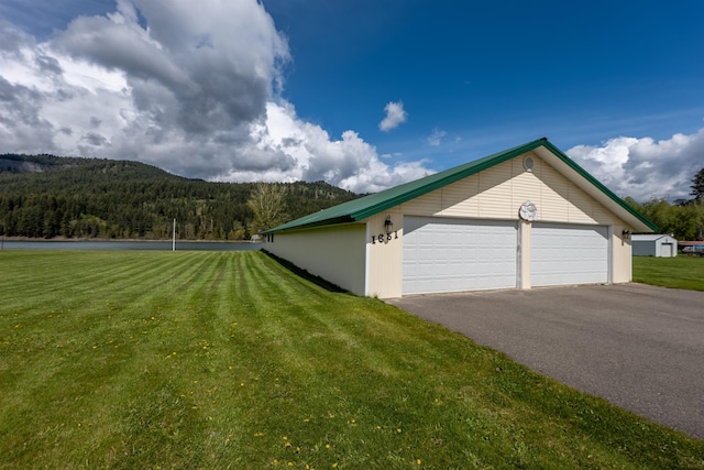 view of home's exterior with a garage, a mountain view, a lawn, and an outbuilding