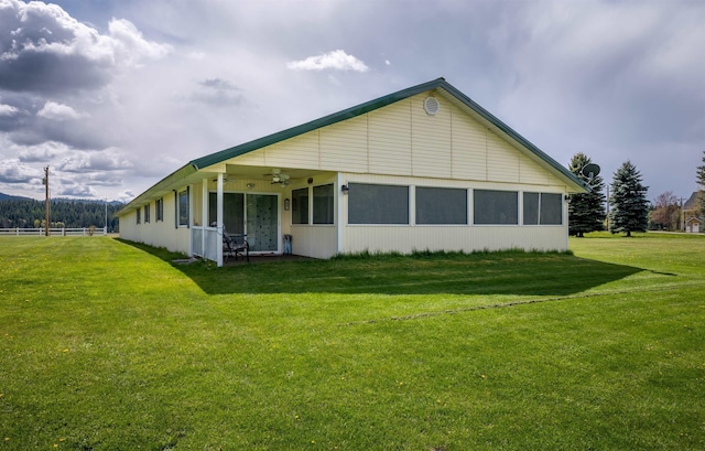 back of house featuring a ceiling fan and a lawn