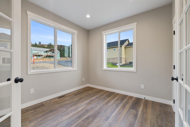 empty room featuring french doors, dark wood-style flooring, visible vents, and baseboards