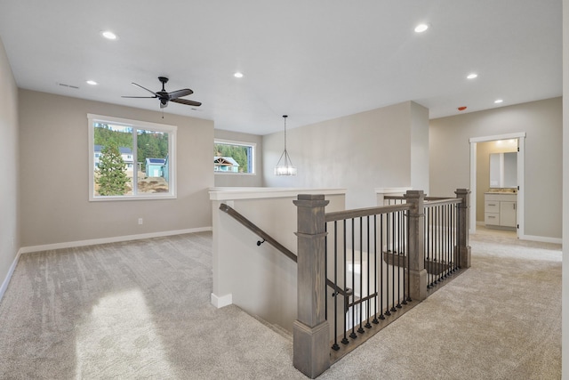 hallway with light carpet, baseboards, an upstairs landing, and recessed lighting