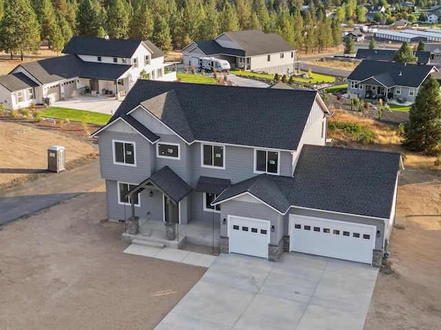 view of front facade featuring a garage, concrete driveway, a shingled roof, and a residential view