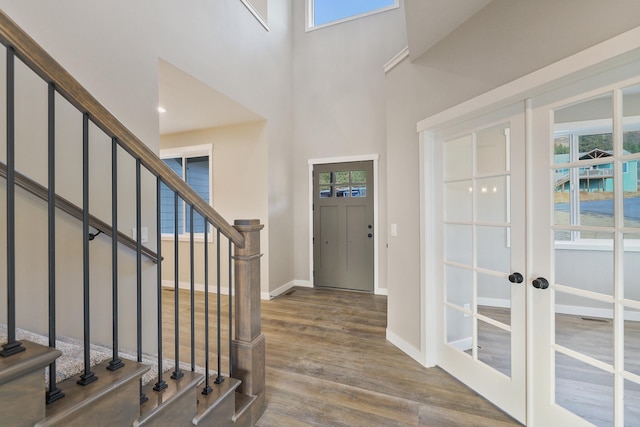 entryway with wood finished floors, a towering ceiling, baseboards, stairs, and french doors