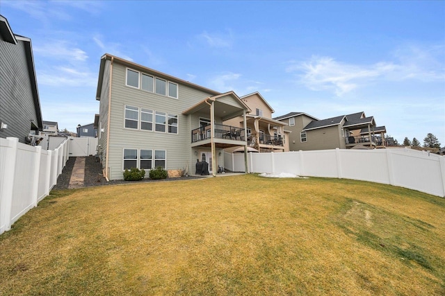 back of house with a yard, a fenced backyard, and a balcony