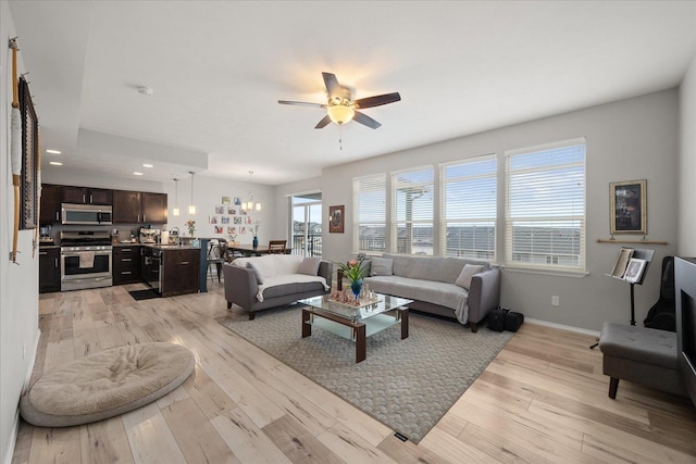 living room featuring recessed lighting, light wood-style flooring, baseboards, and ceiling fan with notable chandelier