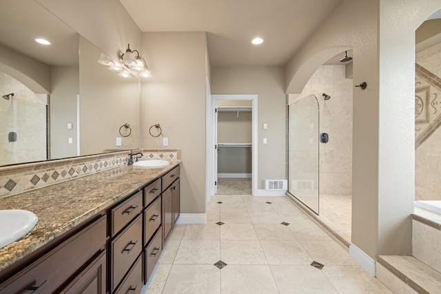 bathroom featuring a tile shower, a sink, double vanity, tile patterned floors, and visible vents