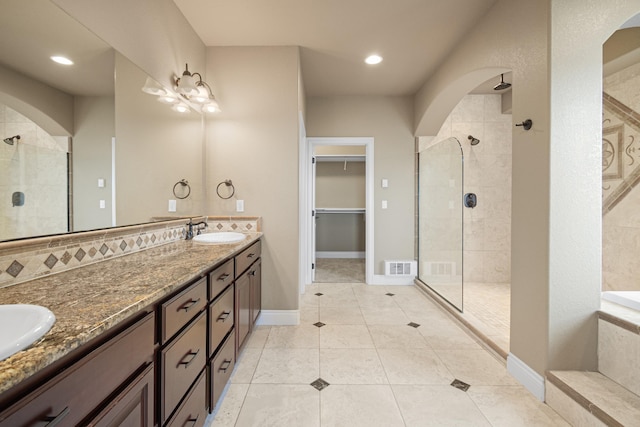 full bathroom featuring double vanity, visible vents, a sink, and tiled shower