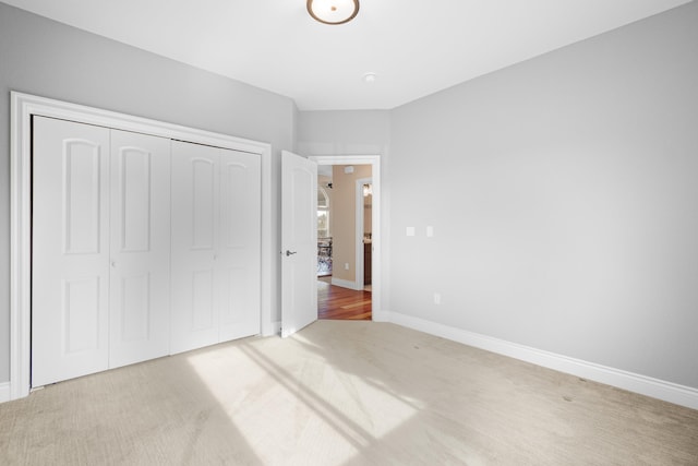 unfurnished bedroom with carpet, a closet, and baseboards