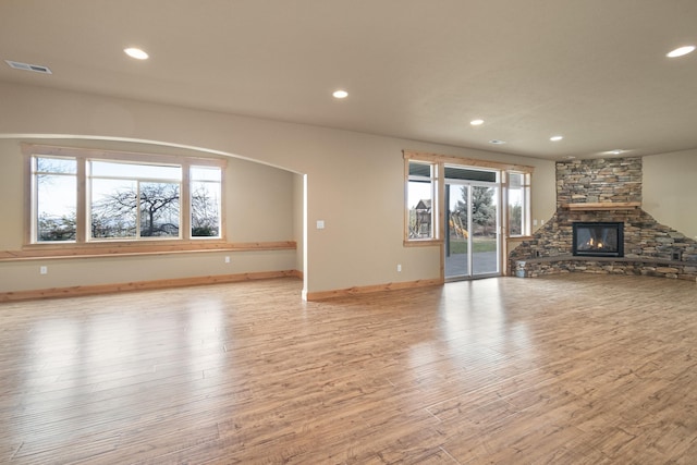 unfurnished living room with light wood-type flooring, recessed lighting, visible vents, and a stone fireplace