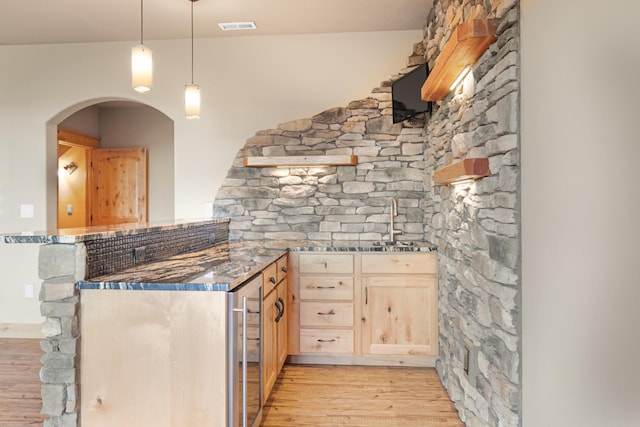 kitchen with visible vents, a peninsula, beverage cooler, light wood-style floors, and light brown cabinets