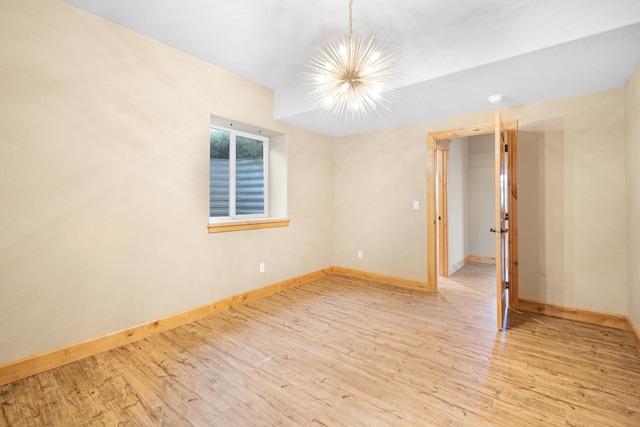 empty room with a notable chandelier, baseboards, and wood finished floors