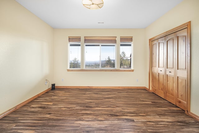unfurnished bedroom featuring baseboards, visible vents, wood finished floors, and a closet
