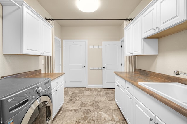 laundry room with a sink, stone finish flooring, cabinet space, and washing machine and clothes dryer