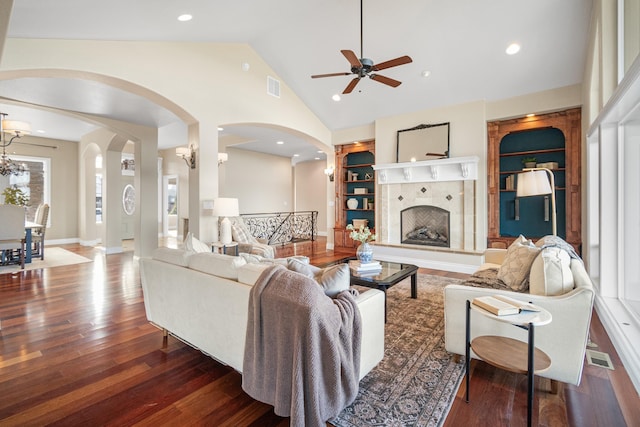 living room featuring built in shelves, a tiled fireplace, wood finished floors, and visible vents