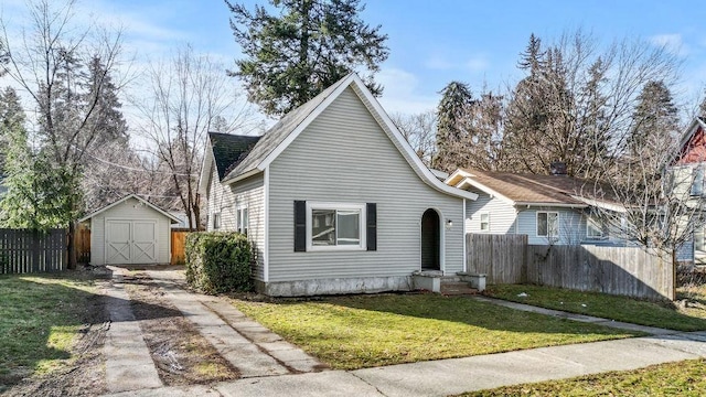 bungalow-style house featuring an outbuilding, a storage shed, a front yard, fence, and driveway