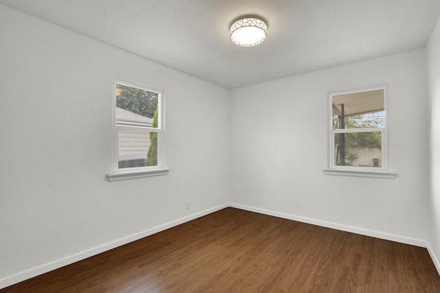 spare room with baseboards, dark wood-style floors, and a healthy amount of sunlight