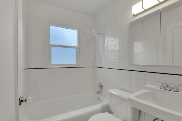 bathroom with tile walls, tasteful backsplash, bathtub / shower combination, toilet, and a sink