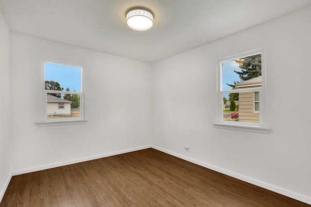 spare room with a healthy amount of sunlight, wood finished floors, and baseboards