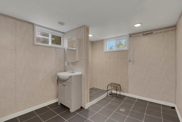 bathroom with baseboards, tiled shower, vanity, and tile patterned floors