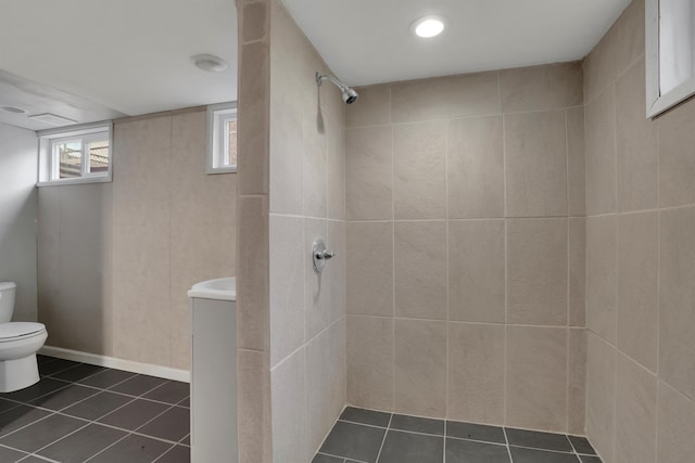 bathroom featuring baseboards, a tile shower, toilet, and tile patterned floors