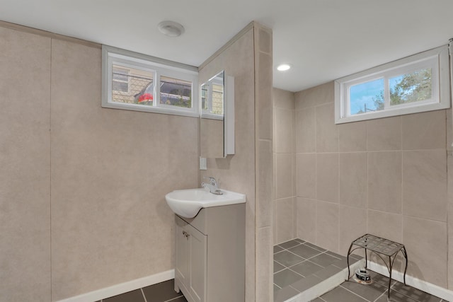 bathroom with baseboards, tiled shower, vanity, and tile patterned floors