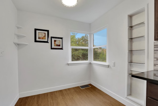 unfurnished dining area featuring light wood-style floors, baseboards, and visible vents