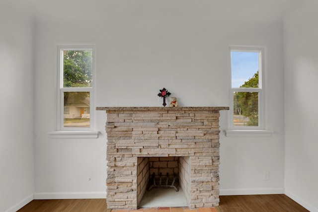 room details featuring a stone fireplace, wood finished floors, and baseboards