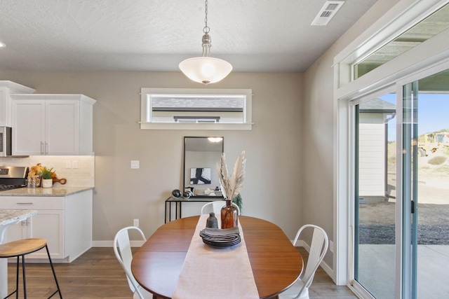 dining room with dark wood-style floors, visible vents, and baseboards