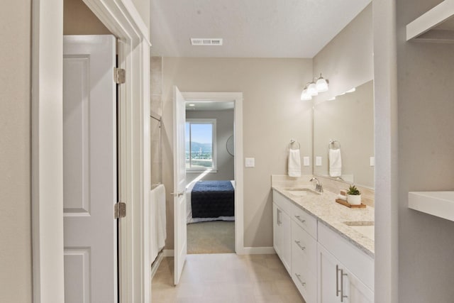 ensuite bathroom with double vanity, baseboards, visible vents, ensuite bathroom, and a sink