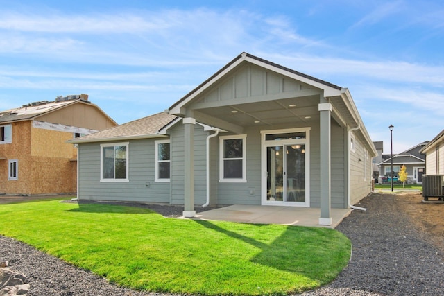 back of house featuring board and batten siding, a yard, a patio, and central AC unit