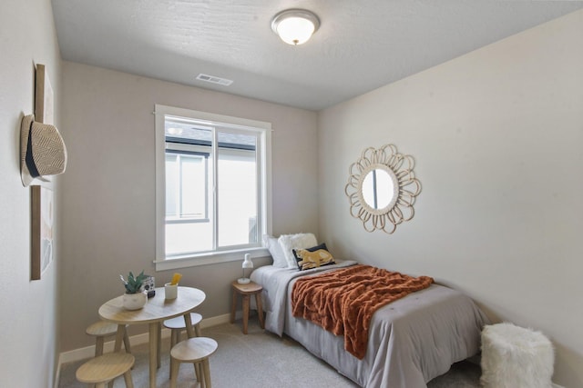 carpeted bedroom with visible vents, baseboards, and a textured ceiling