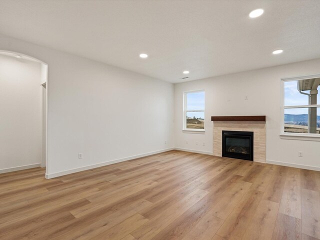 living area featuring a wealth of natural light, a brick fireplace, baseboards, and wood finished floors