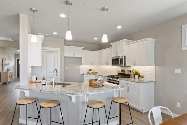 kitchen with appliances with stainless steel finishes, a sink, decorative backsplash, and a breakfast bar area