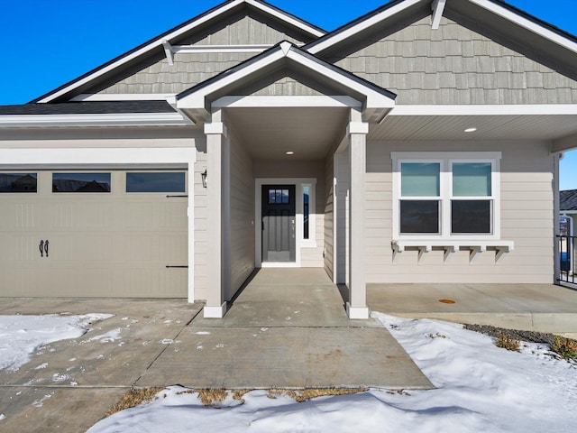 snow covered property entrance featuring a garage