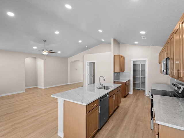 kitchen with arched walkways, appliances with stainless steel finishes, an island with sink, and a sink