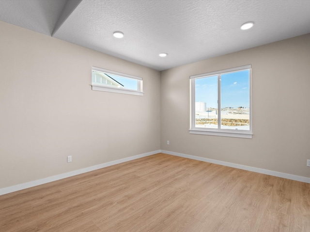 unfurnished room with baseboards, a textured ceiling, recessed lighting, and light wood-style floors