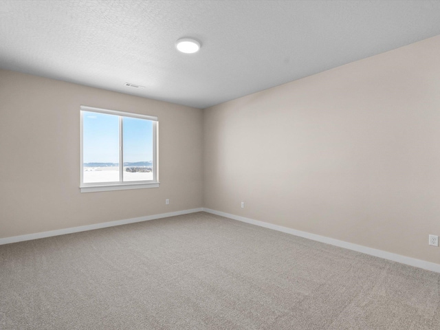 carpeted empty room with a textured ceiling, visible vents, and baseboards