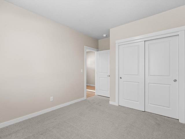 unfurnished bedroom featuring carpet, a closet, and baseboards