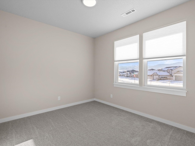 spare room featuring baseboards, visible vents, and carpet flooring