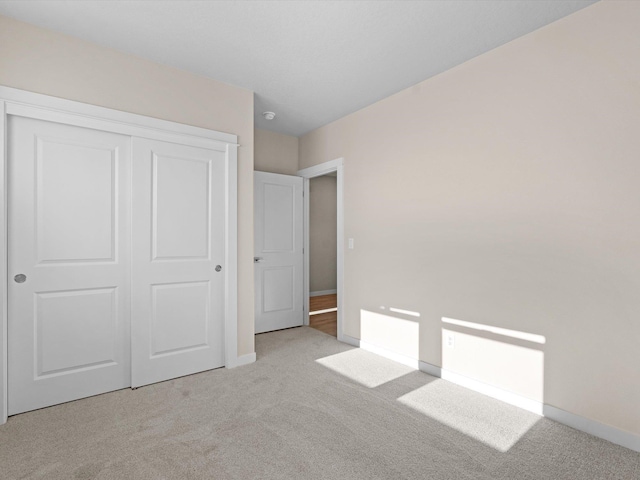 unfurnished bedroom featuring carpet floors, a closet, and baseboards