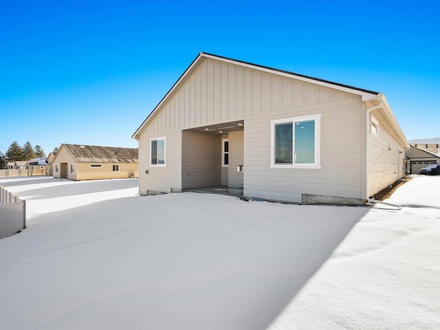 back of house featuring board and batten siding and fence