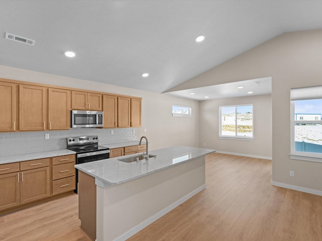 kitchen with lofted ceiling, visible vents, light wood-style flooring, appliances with stainless steel finishes, and a sink